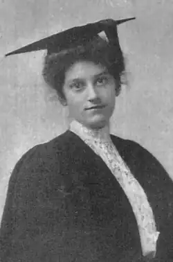 A young white woman with dark hair, wearing academic cap and gown