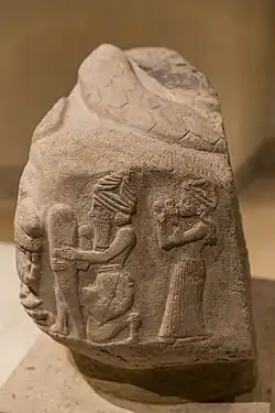 A God putting a foundation nail in the ground, protected by a Lama goddess, in front of a roaring lion. Coiled snake on top. Inscriptions in Linear Elamite and Akkadian. Time of Puzur-Inshushinak, circa 2100 BC, Louvre Museum.[26]