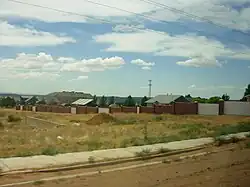 A picture of a compound of the former home of Jeffs in Colorado City, with a grass meadow and a road in the foreground