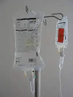 Photograph of two intravenous solution bags hanging from a pole.
