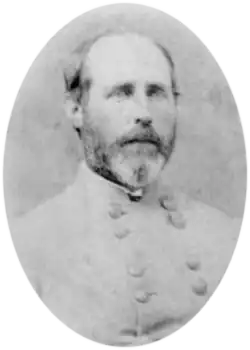 Oval black and white photo shows a balding man with a moustache and beard. He wears a gray military uniform.