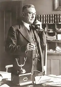 A photograph of Josef Hoop standing while on the telephone in 1945.