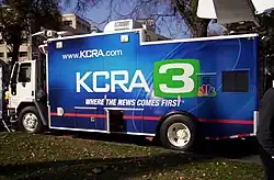 A large truck with mounted satellite dish and wrapped in KCRA livery featuring the station's logo
