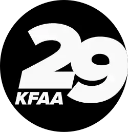 A black circle containing a cut out italicized bold sans serif numeral 29, the 2 above and to the left of the 9. Beneath the 2 are the letters K F A A, smaller but in the same typeface.