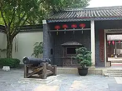 The front entrance of a building labelled "Almshouse" with a cannon in front of it.