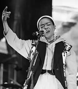 Black and white image of Lauryn Hill closing her eyes while singing into a microphone.