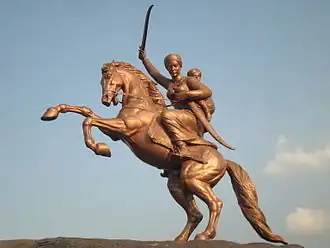 Golden statue of the Rani of Jhansi armed with a sword astride a rearing horse