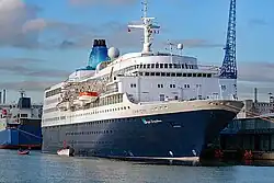 Passenger ship with lifeboats swung out and one lowered to the water