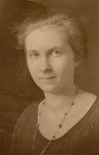 A teenage girl with her hair tied back in a bun, wearing a beaded necklace.