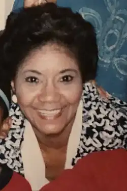 A smiling Black woman wearing a print jacket