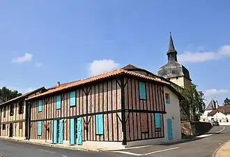 A timbered building and the church tower in Magescq
