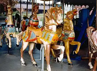 A brown carousel horse with a yellow saddle and green bridle on a historic carousel horse