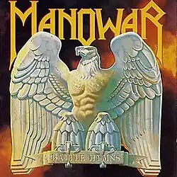 A marble statue of an eagle with prominent human-like chest muscles, with a logo reading "MANOWAR"; the statue's label reads "BATTLE HYMNS".