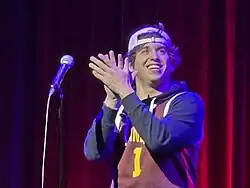 Hernández standing on stage, clapping behind a microphone