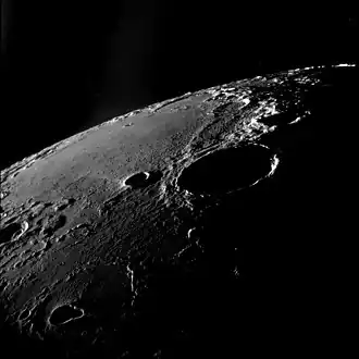 Oblique view facing southeast, from Apollo 11. The large crater right of center is Theophilus, and Mädler is to its left. Fracastorius is near the central horizon, and the white mountain on the horizon at right is part of the Rupes Altai. The teardrop-shaped crater in the lower left is Torricelli.