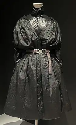 Black coatdress made to look like a black plastic bin bag, with belt made to look like rope with carabiner for buckle