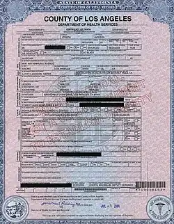 A white piece of paper with personal information about the death of a person. The paper's writing is all in black and has multiple sections blacked out.
