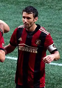A soccer player is wearing an Atlanta United jersey and the captain's arm-band.