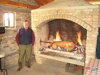 Piglet being roast over open flames in fireplace