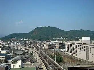 Mt. Shinobu rises from the center of the city of Fukushima. Train tracks can be seen going through a tunnel in the mountain.