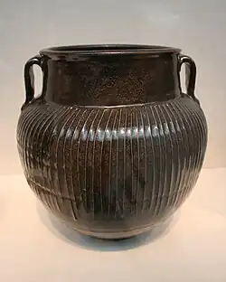 Black vase, with white slip in between the ribs