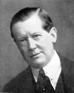 middle-aged white man, clean shaven with full head of neat dark hair