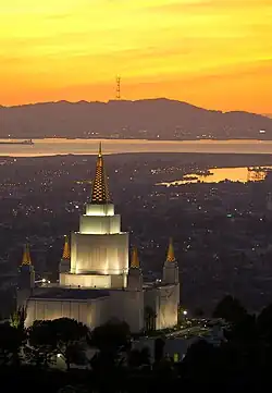San Francisco's three pronged Sutro Tower on a mountain in the distance, with the Oakland Califorina Temple visible in the foreground.
