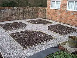 Parterre beds laid out ready for planting, with paths gravelled. One half of a symmetrical design flanking a path shown