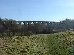 stone viaduct with multiple arches, partly obscured by trees