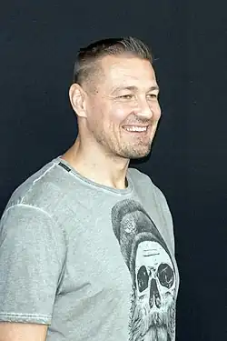 profile photo of a grinning Petr Jákl, wearing a grey print t-shirt