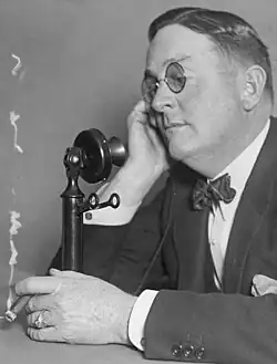 Doyle olds his cigar while using the telephone