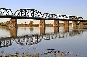 Four truss sections of a railway bridge, supported by stone pillars.