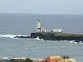 The lighthouse in Praia Harbour with a tiny view of the city