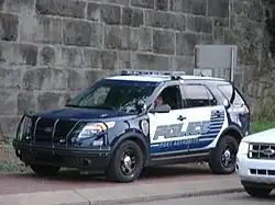 A marked PAPD Ford Police Interceptor Utility patrol vehicle, parked on a sidewalk and occupied by a solo officer.