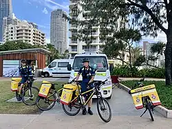 2 Paramedics with bicycles that have large packs on the rear, carrying emergency equipment.
