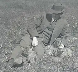 The wildlife illustrator Robert Bruce Horsfall sitting on the grass with three cougar cubs.