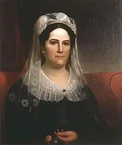 Woman in black with white bonnet and lace collar looking forward