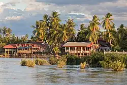 View from Don Det: river bank of the twin island Don Khon, with stilt wooden houses.