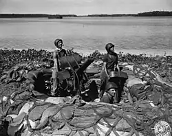 Black and white photograph of three men with a large gun