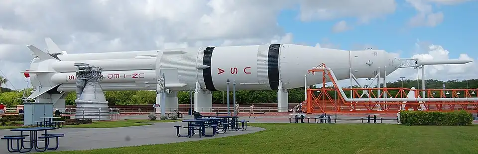 A large white rocket, with the letters U, S and A written vertically down it in red, lies on its side outdoors