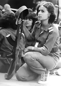 Shadia Abu Ghazaleh, kneeling down and holding a rifle