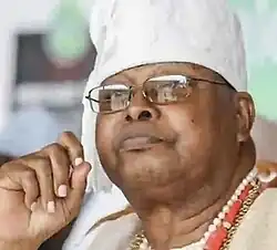 African male wearing spectacles in white robes and hat of traditional costume