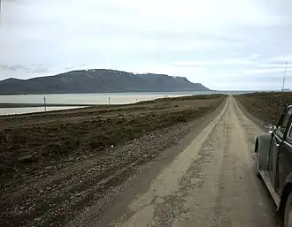 A dirt road leading towards the sea and hills