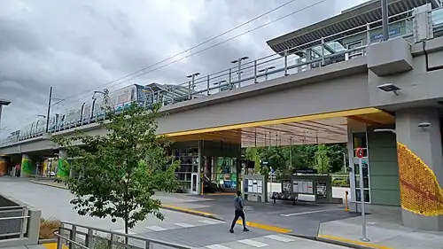 South Bellevue station shortly after opening in April 2024. The modern light rail station has a colorful mural and a train passing overhead.