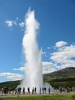 Bystanders watch a nearby geyser erupting.