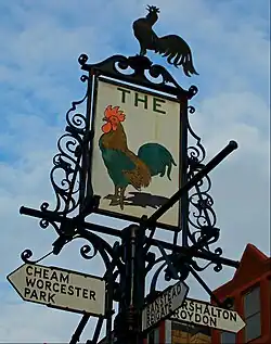 A finger post in Sutton town centre, London, incorporating the sign of the former Cock inn