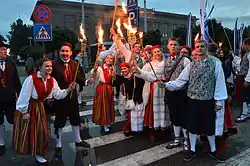 Image 26Estonian national clothes are a fine example of change in clothing after the Industrial Revolution. They changed considerably during 18th and 19th century with the addition of new types of colors (like aniline dyes), placement of colors (like lengthwise stripes) and with the addition of new elements (like waistcoats). By the end of the 19th century they went out of use in most of the country (except more remote places as in Kihnu island) and it was only in mid 20th century when they once again gained popularity and now as a formal clothing. Members of University of Tartu Folk Art Ensemble wearing clothes specific to Kihnu island, Tori Parish (women in red skirts) and Tõstamaa area (men in brown clothing). (from History of clothing and textiles)