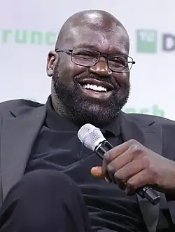 Head and shoulders photograph of O'Neal smiling and holding a microphone