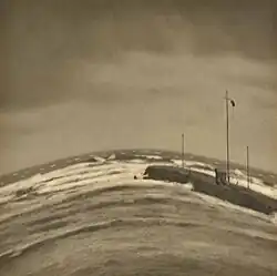 Photograph looking out to the sea, with a breakwater and, above this, a windsock. See also the adjacent text.