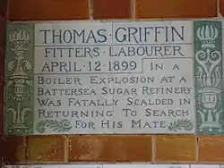 A tablet formed of two large tiles, bordered by green flowers in the style of the Arts and Crafts movement